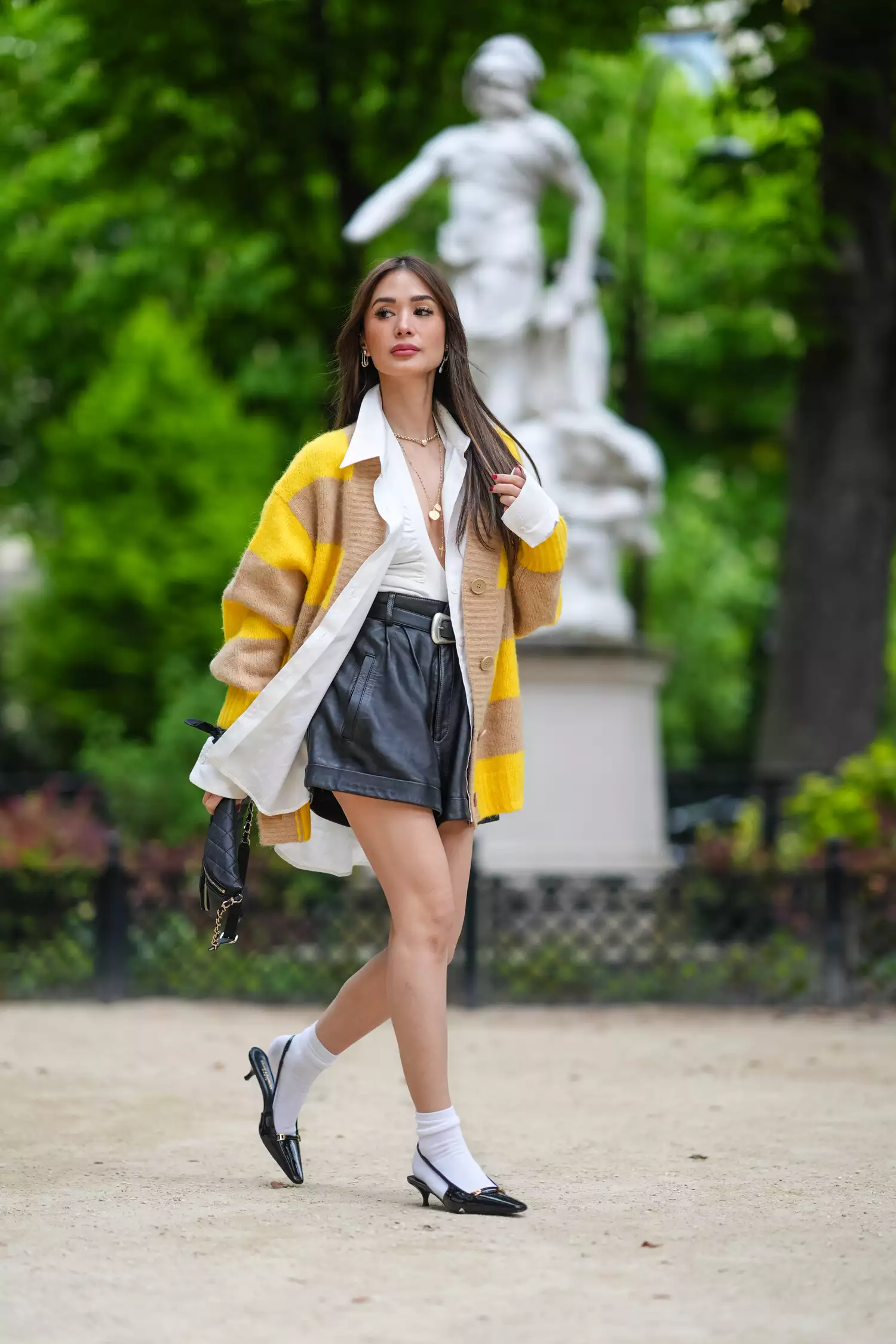 woman wearing black kitten heels, black leather shorts, and a yellow and brown striped cardigan